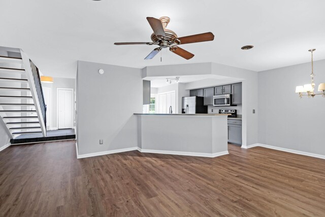 unfurnished living room with dark hardwood / wood-style flooring and ceiling fan with notable chandelier