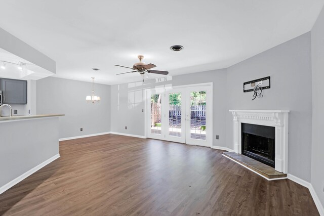 unfurnished living room featuring sink, ceiling fan with notable chandelier, dark hardwood / wood-style flooring, and a tile fireplace