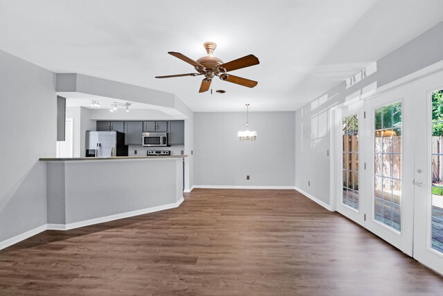 unfurnished living room with dark hardwood / wood-style flooring and ceiling fan with notable chandelier