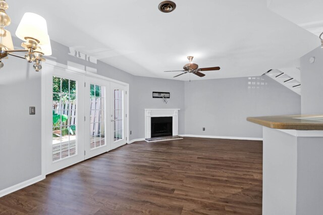 unfurnished living room featuring ceiling fan with notable chandelier and dark hardwood / wood-style flooring