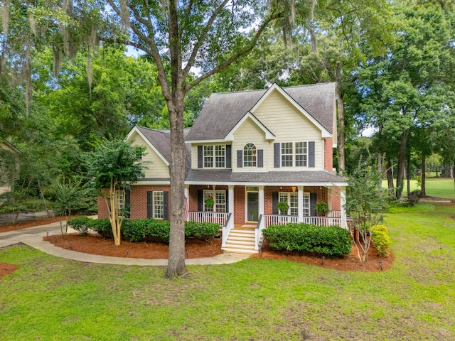 5195 Forest Oaks Dr, Hollywood, SC 29449 - view of front of house with covered porch, a shingled roof, brick siding, and a front lawn