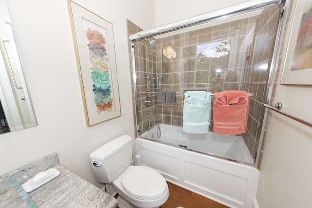 bathroom featuring toilet and bath / shower combo with glass door