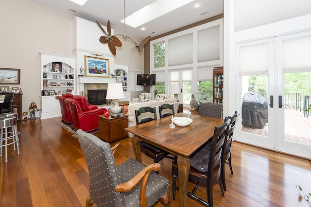 dining space with a skylight, wood-type flooring, ceiling fan, and a high ceiling