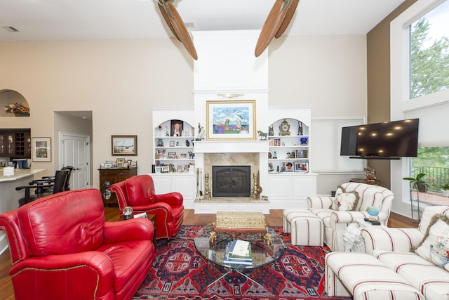 living room with a fireplace, hardwood / wood-style flooring, built in shelves, and a high ceiling