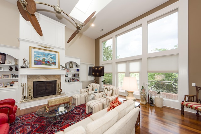 living room with built in features, dark hardwood / wood-style floors, a high ceiling, and a fireplace