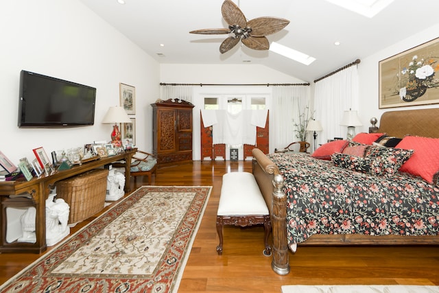 bedroom with ceiling fan, vaulted ceiling with skylight, and hardwood / wood-style flooring