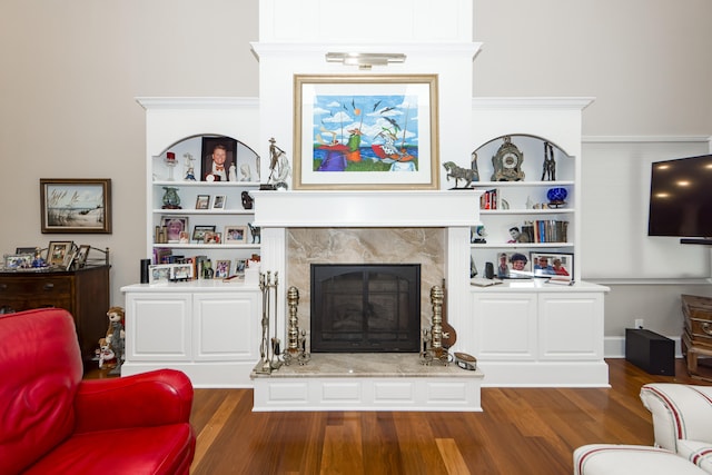 living room with built in shelves, a high end fireplace, and dark wood-type flooring