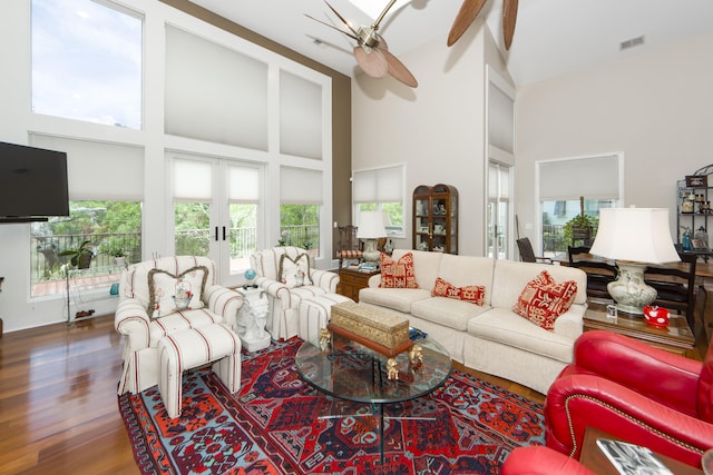 living room featuring french doors, ceiling fan, hardwood / wood-style flooring, and a high ceiling