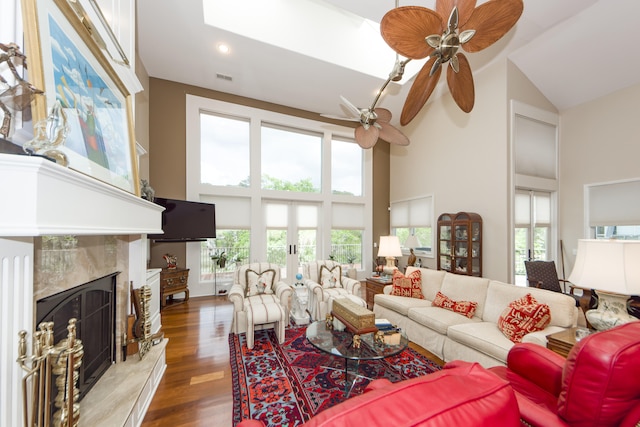 living room with dark hardwood / wood-style floors, ceiling fan, a wealth of natural light, and a high end fireplace