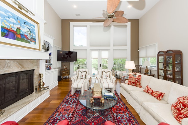 living room featuring a healthy amount of sunlight, dark hardwood / wood-style floors, ceiling fan, and a high ceiling