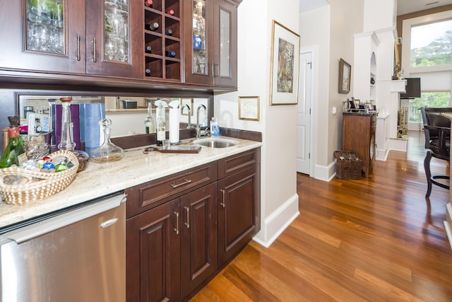 bar featuring hardwood / wood-style floors, light stone counters, sink, and dark brown cabinetry