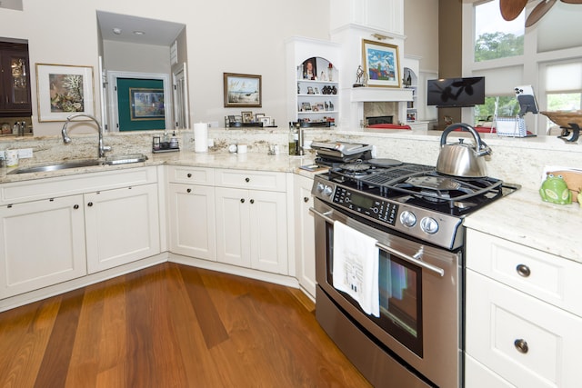 kitchen featuring dark hardwood / wood-style flooring, stainless steel range with gas cooktop, sink, and white cabinets