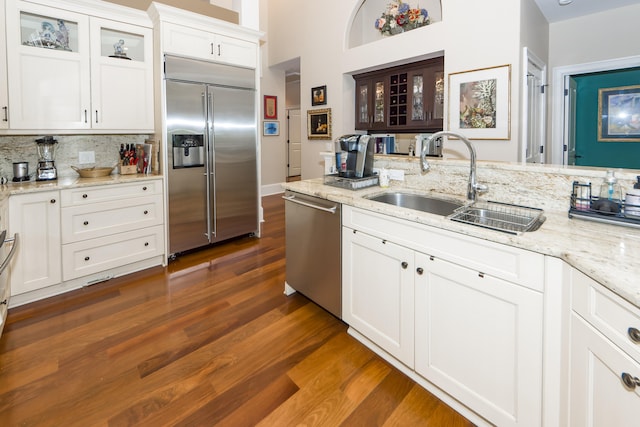 kitchen featuring light stone counters, white cabinets, sink, dark hardwood / wood-style flooring, and stainless steel appliances