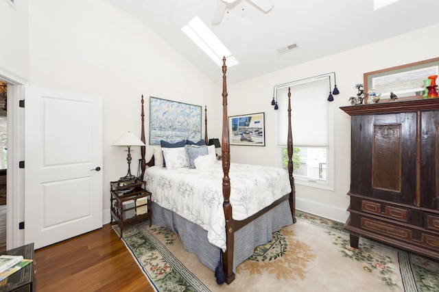 bedroom with dark hardwood / wood-style flooring, lofted ceiling with skylight, and ceiling fan