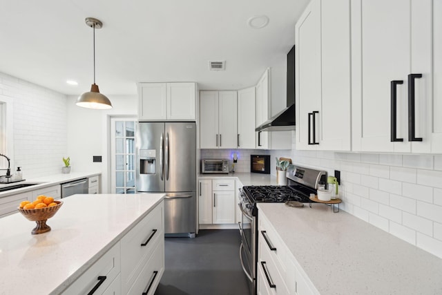 kitchen featuring white cabinets, wall chimney range hood, and appliances with stainless steel finishes