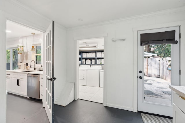 doorway to outside with sink, crown molding, washer and clothes dryer, and a wealth of natural light