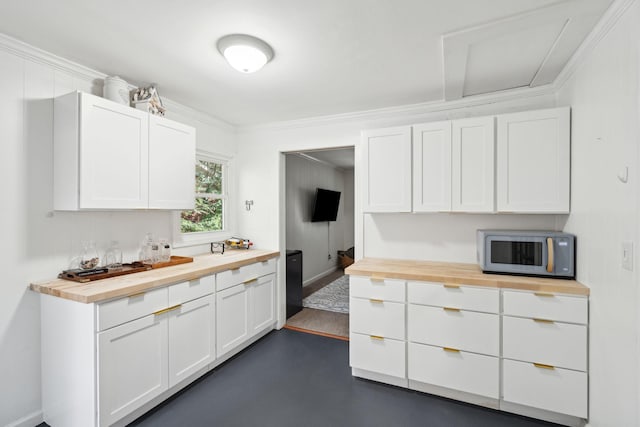 kitchen featuring white cabinetry, crown molding, and wood counters