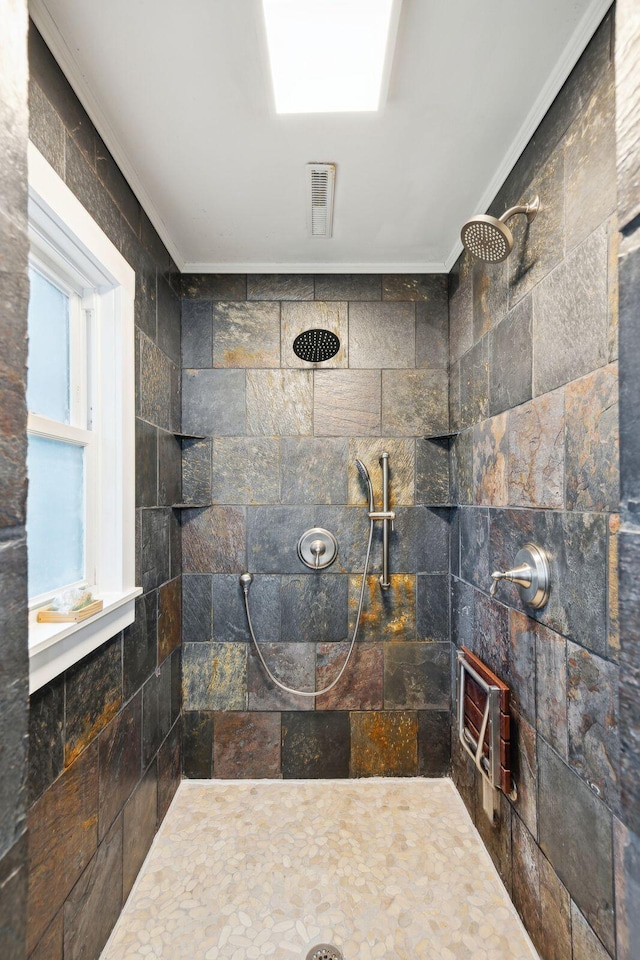 bathroom with a tile shower and ornamental molding