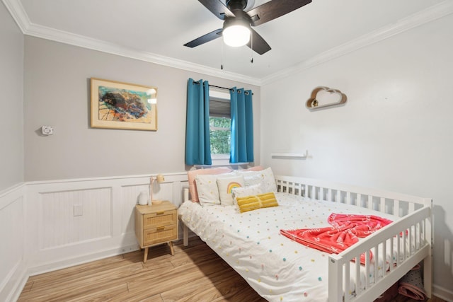 bedroom with light wood-type flooring, ceiling fan, and crown molding