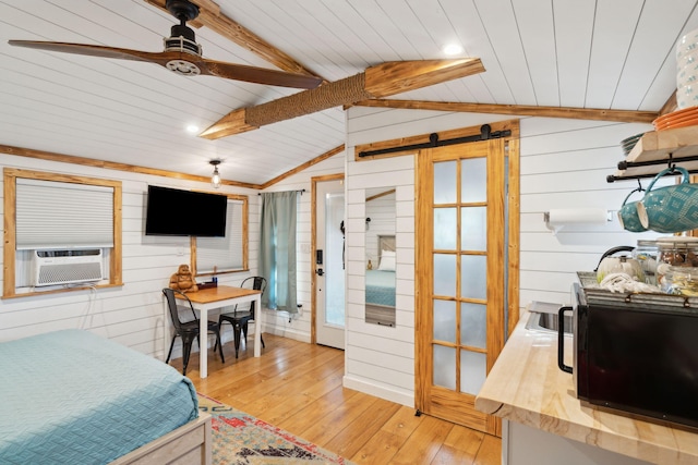 bedroom featuring light hardwood / wood-style floors, cooling unit, wooden walls, and vaulted ceiling with beams