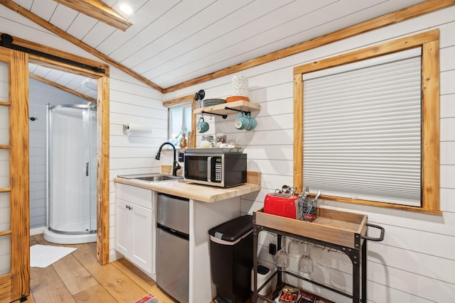 kitchen featuring sink, fridge, white cabinets, lofted ceiling, and light hardwood / wood-style flooring