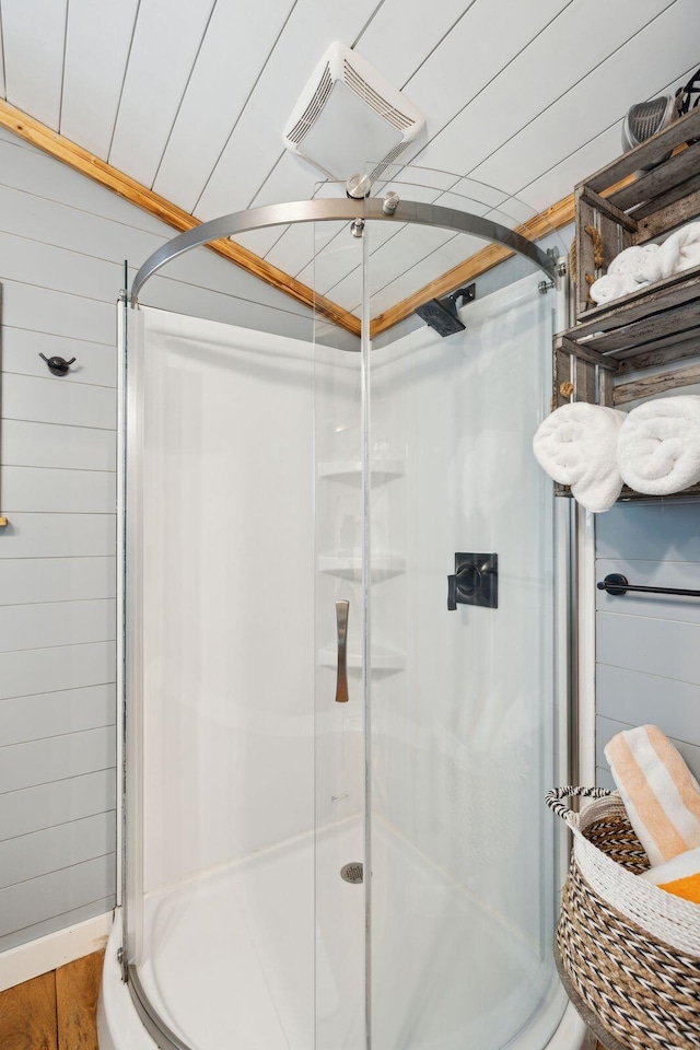 bathroom with a shower with door, wood walls, and wood-type flooring