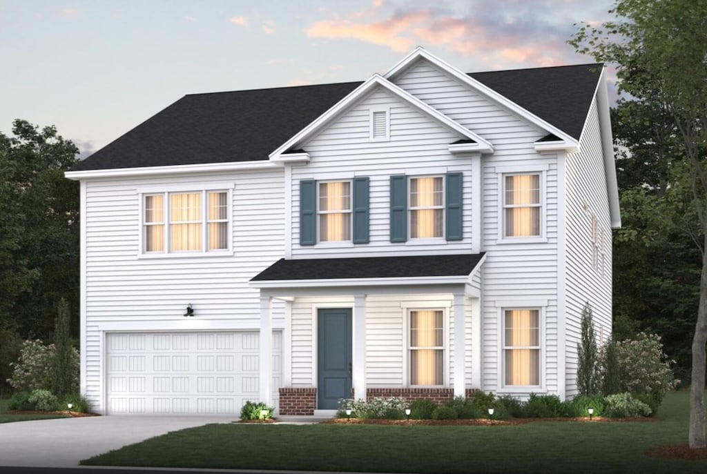 traditional-style house with a garage, concrete driveway, brick siding, and a front lawn