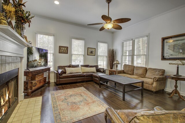 living room featuring hardwood / wood-style flooring, crown molding, a tiled fireplace, and ceiling fan