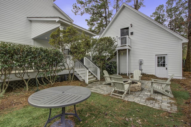 back of property with a fire pit, a patio, and a deck