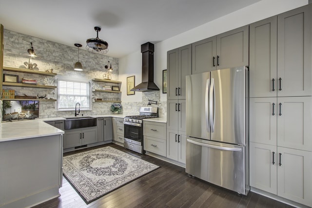 kitchen featuring appliances with stainless steel finishes, sink, gray cabinetry, hanging light fixtures, and wall chimney range hood