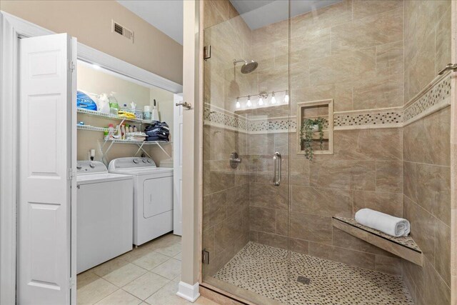 bathroom with tile patterned flooring, a shower with door, and washer and dryer