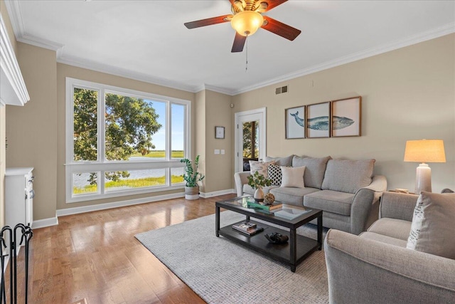 living room featuring light hardwood / wood-style floors, ceiling fan, and crown molding