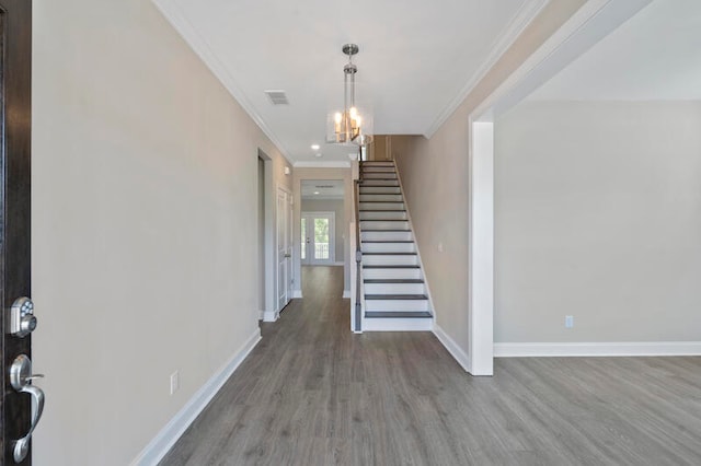 entryway featuring ornamental molding, an inviting chandelier, and wood-type flooring