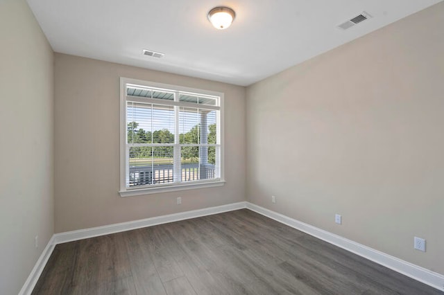 unfurnished room featuring dark wood-style floors, visible vents, and baseboards