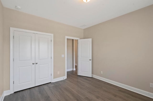 unfurnished bedroom featuring a closet, baseboards, and dark wood-style flooring