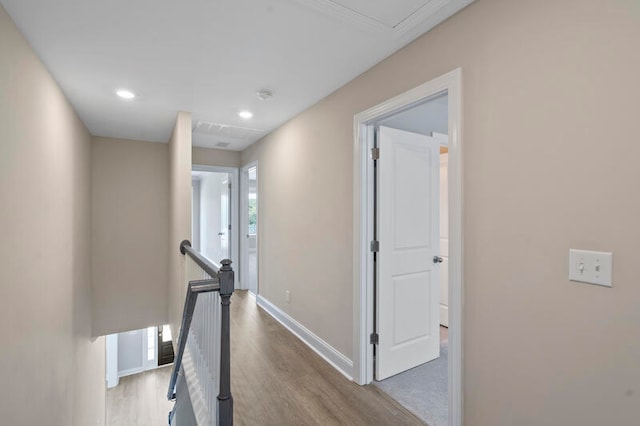 corridor with recessed lighting, wood finished floors, an upstairs landing, and baseboards