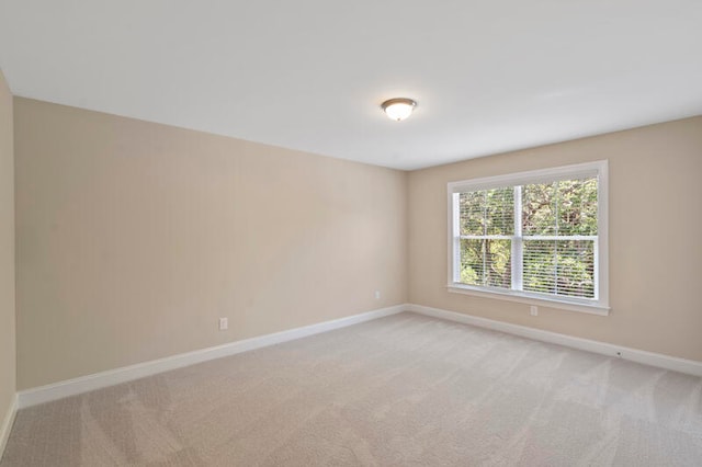 unfurnished room with baseboards and light colored carpet