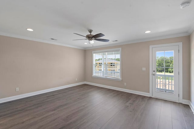 empty room featuring ornamental molding, dark wood finished floors, plenty of natural light, and baseboards