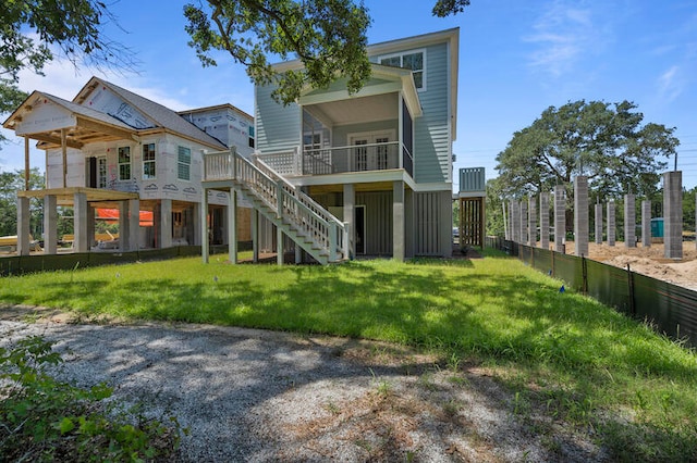 rear view of house featuring stairs and a lawn