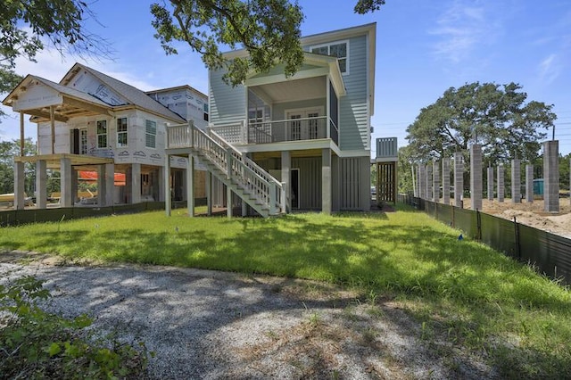 rear view of house featuring stairs and a yard