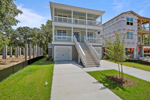 raised beach house featuring a front lawn, a garage, and a balcony