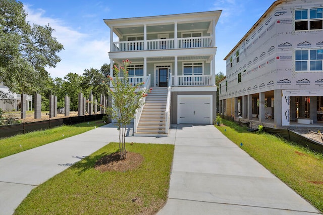 coastal inspired home with a garage, a front lawn, a balcony, and covered porch