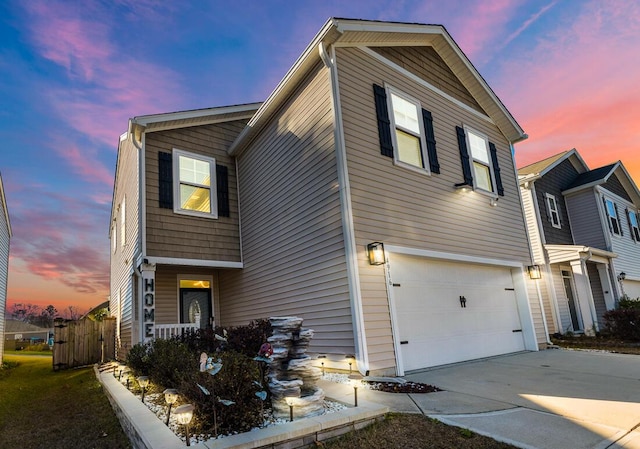 property exterior at dusk with driveway, an attached garage, and fence