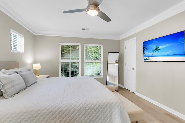 bedroom with baseboards, multiple windows, ornamental molding, and wood finished floors