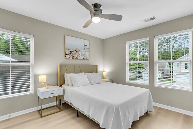 bedroom with baseboards, ceiling fan, light wood-style flooring, and visible vents