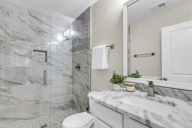bathroom featuring visible vents, a marble finish shower, toilet, and vanity