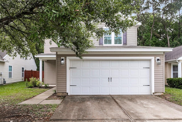 view of front facade with an attached garage, fence, and concrete driveway