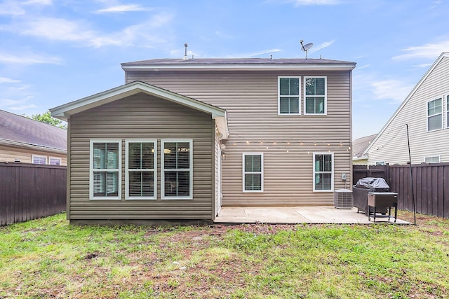 rear view of house with a fenced backyard, a patio, a yard, and central AC unit
