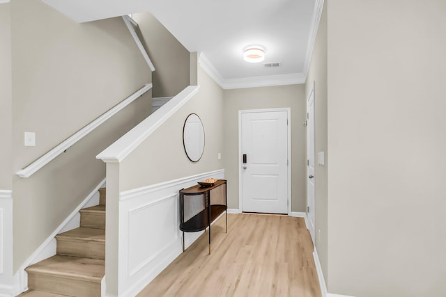 entryway featuring crown molding, stairway, light wood-style floors, and visible vents