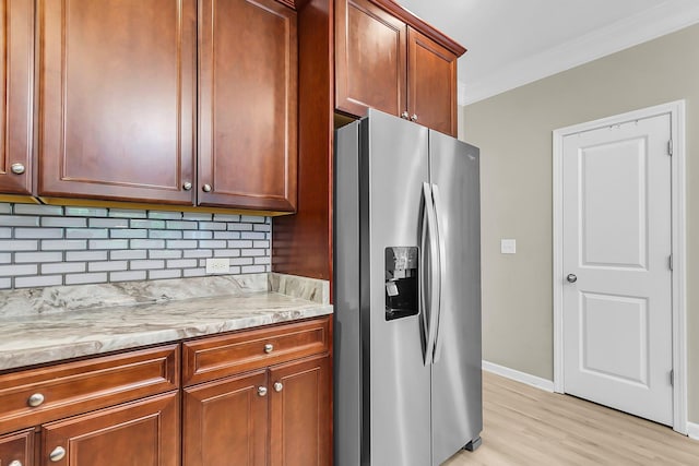 kitchen with crown molding, tasteful backsplash, stainless steel fridge with ice dispenser, baseboards, and light wood finished floors